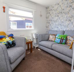 A living room with two gray sofas and a floral wallpaper at Sunny South Shore in Bridlington