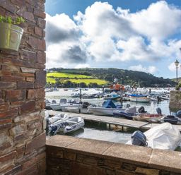 A marina with multiple boats docked and green hills in the background at 7 Island Quay in Salcombe