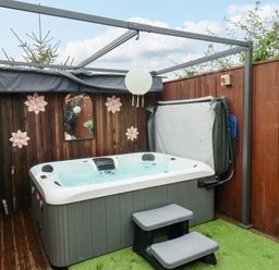An outdoor hot tub with steps and a wooden fence with decorations at Stag Lodge Holiday Retreat in Whitby
