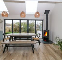 A dining area with a wooden table benches chairs and a fireplace at 11 Capel Farm in Trearddur Bay