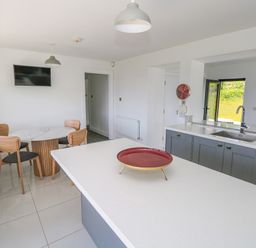 A kitchen with a dining table and chairs a sink and a countertop with a red tray on it at Cushranny Mulranny County Mayo