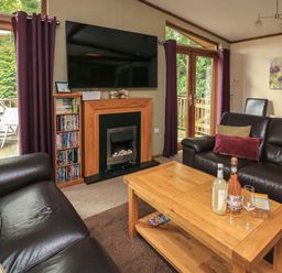 A living room with two leather sofas a wooden coffee table a fireplace and a large wall-mounted tv at Templar Rise 16 - Devon Comfort in Finlakes Holiday Park near Chudleigh