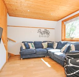 A living room with a blue sectional sofa and cushions next to a large window at Lodge 47 - Primrose Lodge Finlakes Holiday Park near Chudleigh
