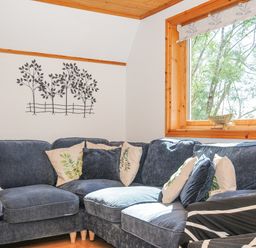 A corner seating area with blue fabric sofas and cushions near a window with a wooden frame at Lodge 47 - Primrose Lodge in Finlakes Holiday Park near Chudleigh