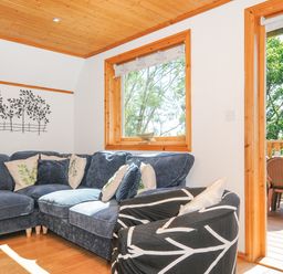 A seating area with a blue corner sofa and a patterned armchair next to a window and an open door leading to a patio at Lodge 47 - Primrose Lodge in Finlakes Holiday Park near Chudleigh