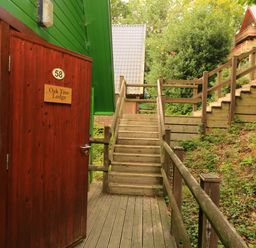 A wooden staircase with handrails leading up beside green and red wooden lodges at Oak Tree Lodge in Finlakes Holiday Park near Chudleigh