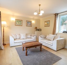 A living room with two sofas a wooden coffee table and framed pictures on the wall at Tiffany's Cottage in Gorleston-On-Sea