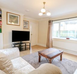 A living room with a couch a wooden coffee table a television on a stand and a bookshelf at Tiffany's Cottage in Gorleston-On-Sea