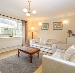 A living room with two sofas a wooden coffee table a floor lamp and framed pictures on the walls at Tiffany's Cottage in Gorleston-On-Sea