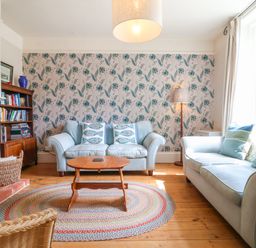 A living room with two sofas a wooden coffee table a bookshelf and a fireplace at Samphire House in Southwold