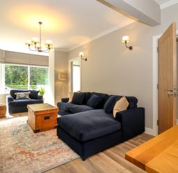 A living room with a navy blue sofa and armchair a wooden coffee table and a large window at Eller Cottage in Windermere