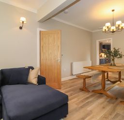 A living room with a dark blue sofa and wooden dining table with benches at Eller Cottage in Windermere