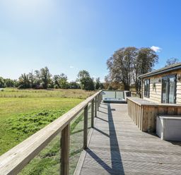 An outdoor deck with a wooden cabin and hot tub at Angel Lodge - No 27 Fornham St Genevieve near Bury St Edmunds