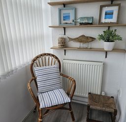 A snug area with a chair and shelf displayed with decorations at Seahorses