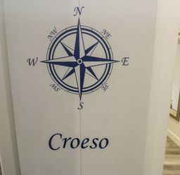 A wall with a compass rose and the word Croeso next to a hallway with a mirror at Sandy Bay Retreat in Benllech