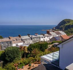 A coastal view with houses and greenery overlooking the sea and cliffs at Combe View in Ilfracombe