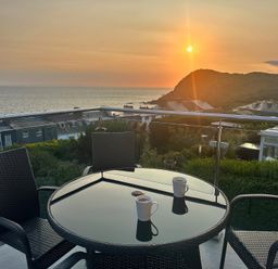 A table and chairs with mugs overlooking the sea at Combe View in Ilfracombe
