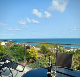 A table with drinks and chairs overlooking the sea at Combe View in Ilfracombe