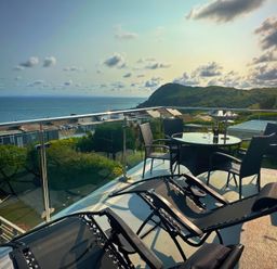 A balcony with deck chairs and table overlooking the ocean at Combe View Ilfracombe