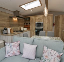 A kitchen and dining area with wooden cabinets a dining table with chairs and a sofa with cushions at Mon in Troutbeck Bridge