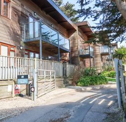 A row of wooden houses with balconies and glass railings at Towan Valley Resort in Porthtowan