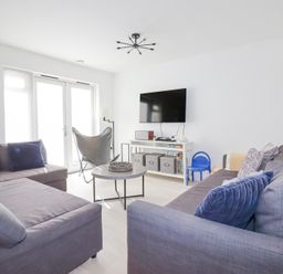 A living room with two gray sofas pillows a wall mounted TV and a round coffee table at Tincroft in Porthtowan