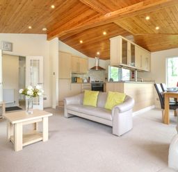 An open plan living room and kitchen with a beige sofa, wooden dining table, TV on a wooden stand and wooden ceiling at Lodge 3 At Pound Farm Crook near Kendal