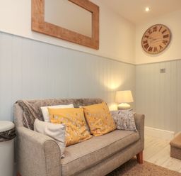 A seating area with a sofa and cushions next to a staircase and a lamp at Little Gem in Whitby