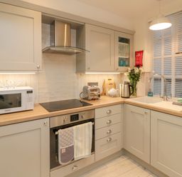 A kitchen with microwave toaster oven kettle sink and cabinets at Little Gem in Whitby