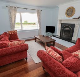 A living room with red sofas wooden coffee table and a fireplace at Cois Leice Cushlecka near Mulranny County Mayo