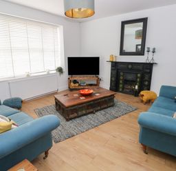 A living room with teal sofas wooden coffee table and television at Bryn Siriol in Narberth