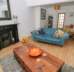 A living room with a blue sofa wooden coffee table and a fireplace at Bryn Siriol in Narberth