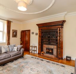 A living room with sofas a patterned rug and a carved wooden fireplace at North Wing in Middleton Hall Estate near Belford