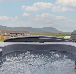 An outdoor hot tub with bubbles and mountains in the background at Lapwing in Chapel Le Dale near Ingleton