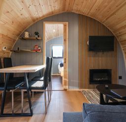 A wooden dining room with a table and four chairs next to a living area with a fireplace and TV at Oyster Catcher in Chapel Le Dale near Ingleton