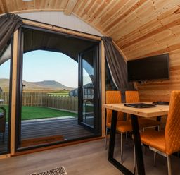 A wooden interior room with orange chairs around a table and a mounted television at Barn Owl in Chapel Le Dale near Ingleton