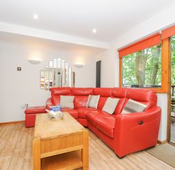 A living room with a red sectional sofa wooden coffee table and a large window at Lodge Nine in Finlake Holiday Park near Chudleigh