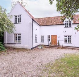 A white cottage with a tiled roof gravel driveway and green bins at White House Cottage in Little Snoring near Fakenham