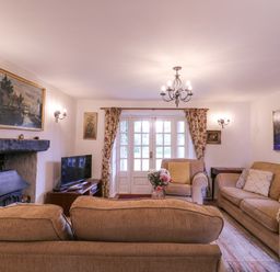 A living room with sofas a fireplace a television and paintings at White House Cottage in Little Snoring near Fakenham