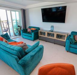 A living room with teal sofas and a large wall mounted television at 17 Cliff Edge in Newquay