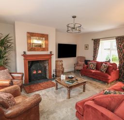 A living room with a fireplace red sofas leather armchairs a wooden coffee table and a television at Manor Farm House in Bere Regis