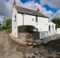 A white detached house on a corner with a stone wall and bushes beside a road at Folly Cottage Llanteg near Saundersfoot