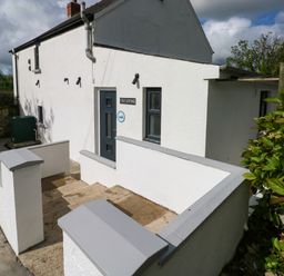 The exterior of a white cottage with a gray door and window at Folly Cottage in Llanteg near Saundersfoot