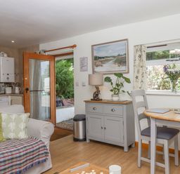 A kitchen and dining area with a sofa pillow and blanket next to a door and window at Dove Cottage Queens Nympton near South Molton