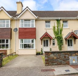 A row of connected houses with bay windows and driveways at 23 Cois Caol in Skibbereen County Cork