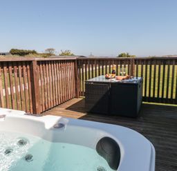An outdoor area with a hot tub and a table set with food and drinks at Hazel Lodge in Whitby