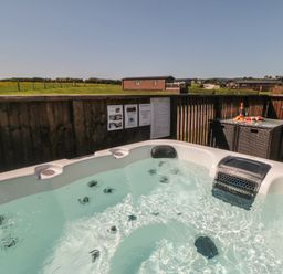 A hot tub with a table and champagne at Willow Lodge in Whitby