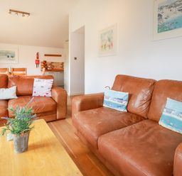 A living room with two brown leather sofas and a wooden coffee table with a potted plant at 3 Lake View in Lanreath