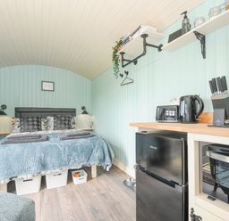 A bedroom with a double bed and bedside lamps beside a kitchen area with a fridge toaster kettle and knife set at Bracken Broad Langdon near Wainhouse Corner