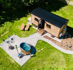 An aerial view of a tiny wooden cabin with two lounge chairs a small patio with a table and chairs and a hot tub at Bracken Broad Langdon near Wainhouse Corner
